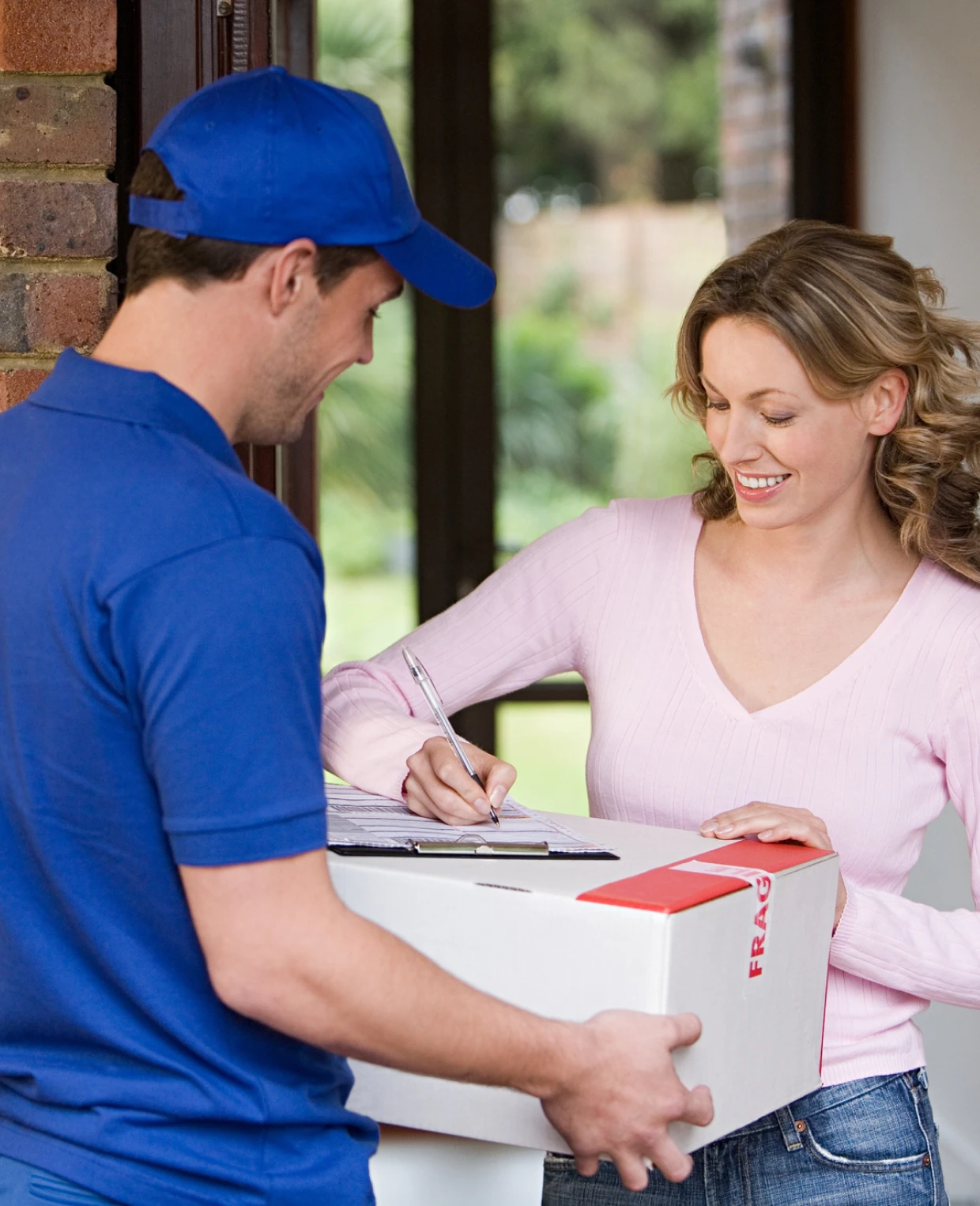 Delivery person handing package to smiling woman.